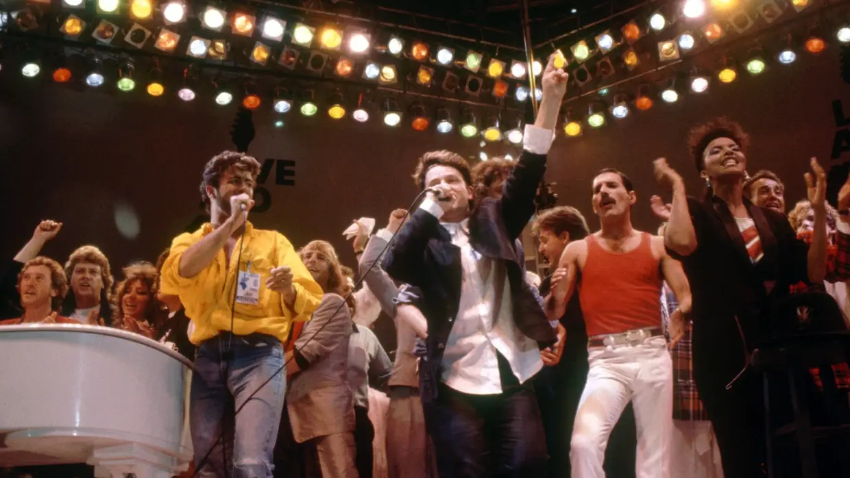 Live Aid, 13 de julho de 1985. Bono entre George Michael e Freddie Mercury