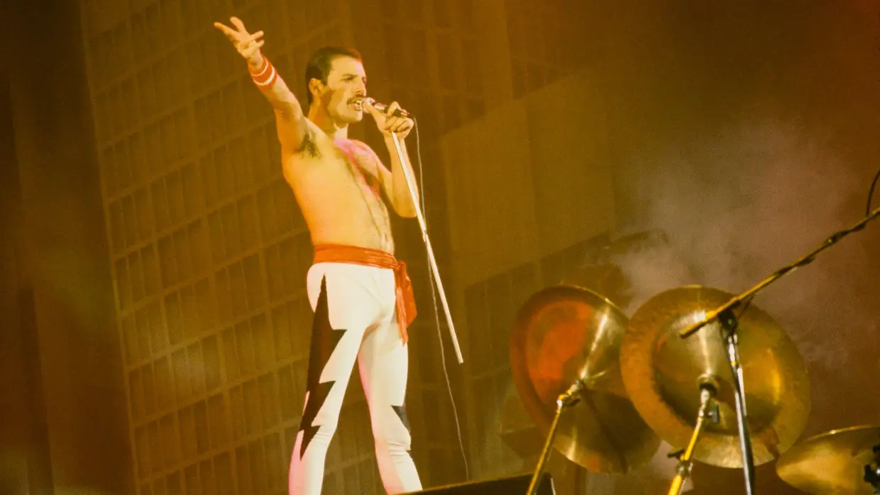 Freddie Mercury numa plataforma sobre a bateria de Roger Taylor