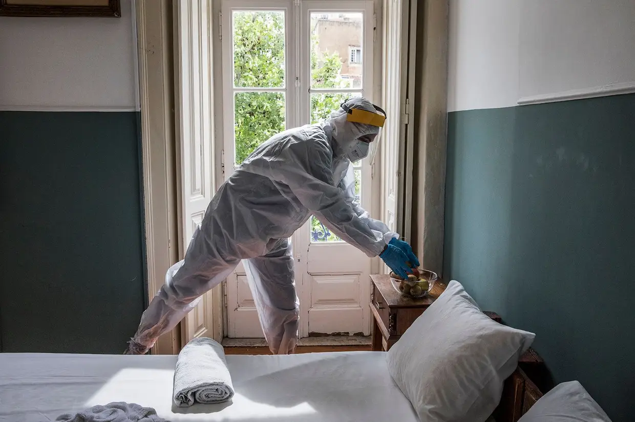 Hugo Marques, chefe da Divisão de Intervenção Social da Junta de Freguesia de Arroios, entra no hostel de fato integral, pés com película aderente, luvas, máscara e viseira. Todos os casos são positivos, mas assintomáticos.