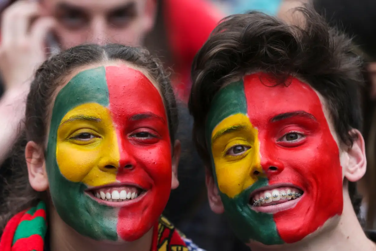 Adeptos com a bandeira nacional pintada na cara, no Porto.