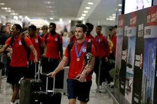 O capitão da seleção inglesa de sub-20, Lewis Cook, a chegar ao aeroporto de Heathrow com o caneco de campeão mundial
