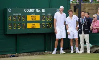 O gigante Isner e Mahut junto ao placard com o score final