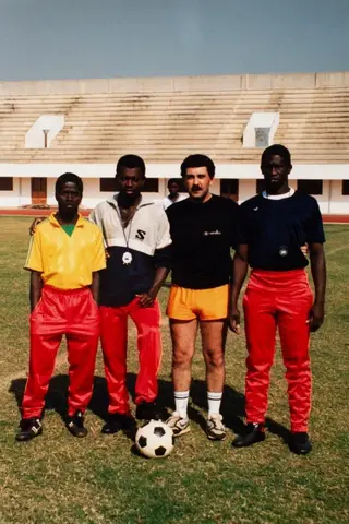 No meio de Domingos Té e João Nafatcha, a sua equipa técnica das seleções de sub-17 da Guiné-Bissau e o roupeiro Melo (de camisola amarela)