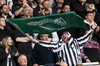 Um adepto do Newcastle com uma bandeira da Arábia Saudita no jogo contra o Tottenham
