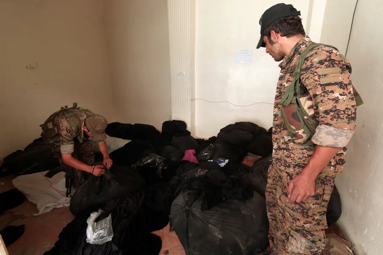 Combatentes das Forças Democráticas da Síria inspecionam sacos com niqabs (véu que cobre o rosto e só mostra os olhos) num centro em Alepo utilizado pela polícia religiosa do Daesh, al-Hisbah.