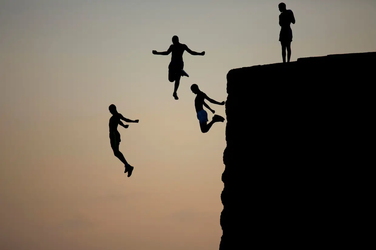 O salto em grupo de três jovens israelitas, do antigo muro que circunda a antiga cidade de Acre para o mar Mediterrâneo.