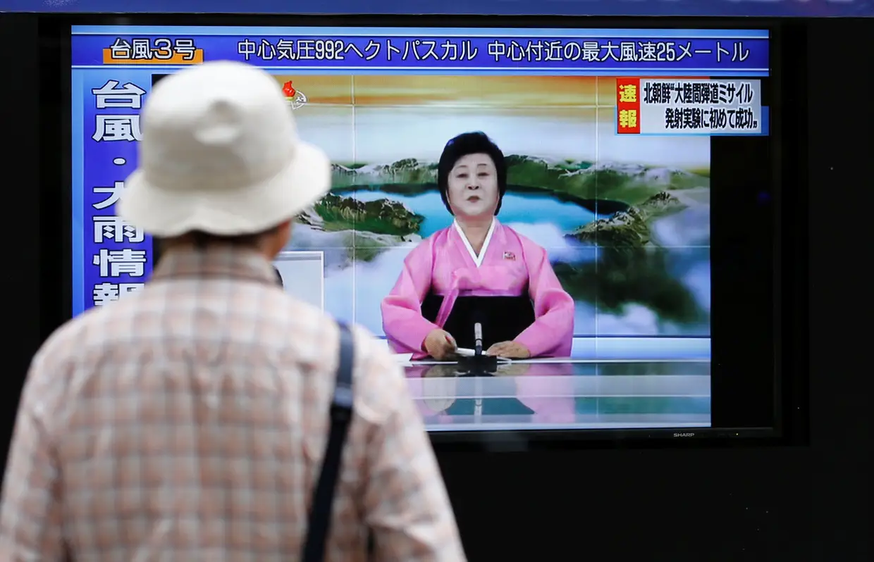 Transeunte de uma rua de Tóquio, Japão, assiste à emissão num dos monitores existentes em vários pontos da cidade.