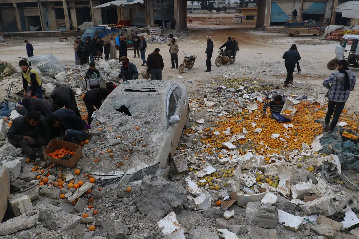 Janeiro - Populares recolhem laranjas num mercado alvo de um bombardeamento aéreo na província de Idlib, Síria.