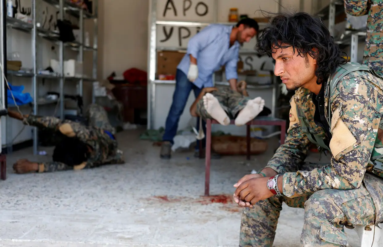 Junho - Militar das Forças Democráticas sírias espera que os seus companheiros recebam assitência médica em Raqqa, depois de terem sido alvo de ataque de ataque do Daesh.