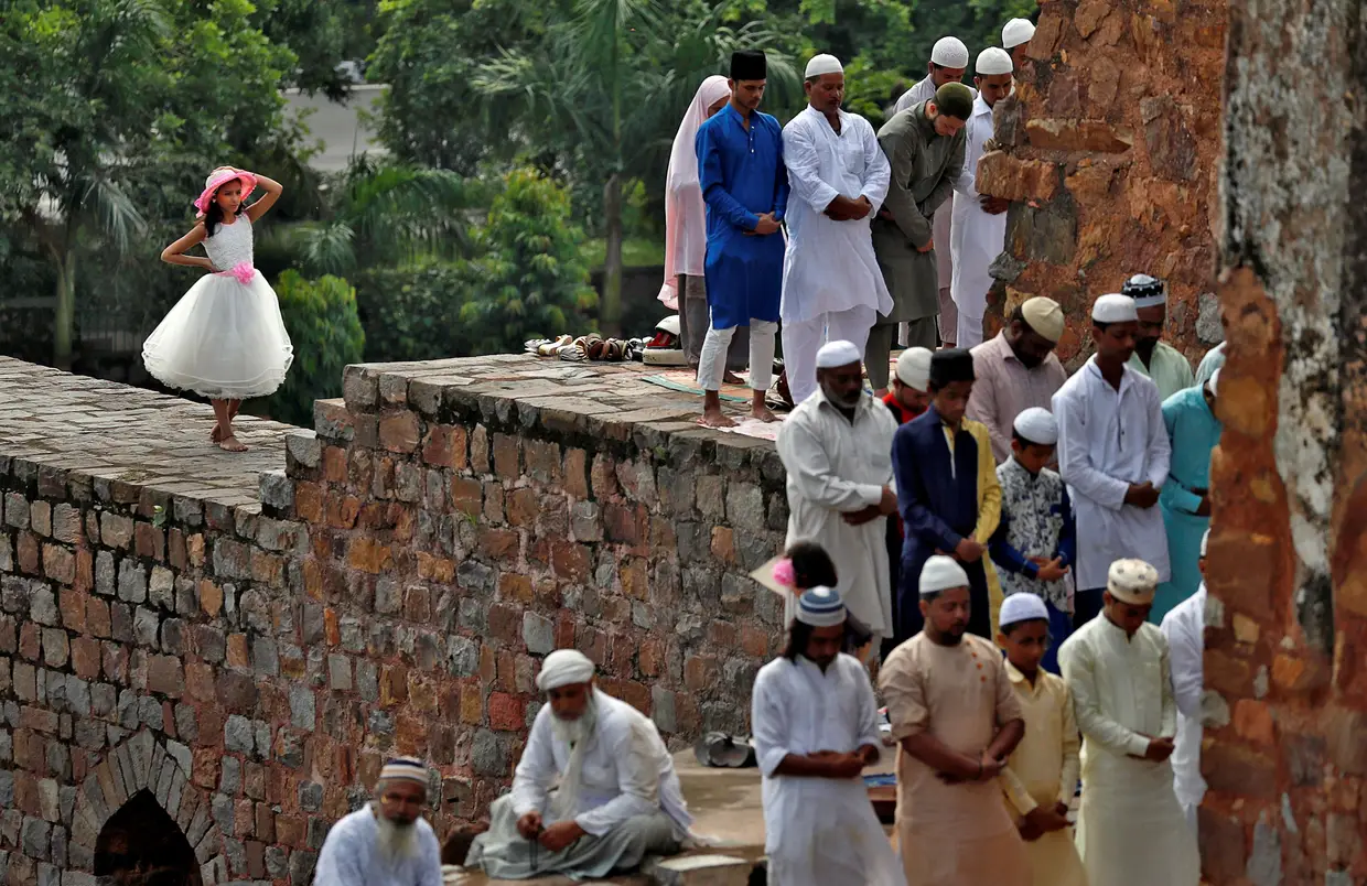 Setembro - Rapariga observa um momento de oração de um grupo de homens muçulmanos no Festival Eid al-Adha, em Nova Deli, Índia.