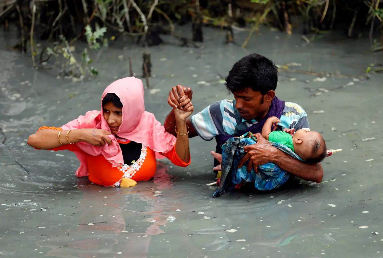 Setembro - Refugiados Rohingya em fuga de Myanmar cruzam o rio com uma criança nos braços, na esperança de chegar ao Bangladesh.