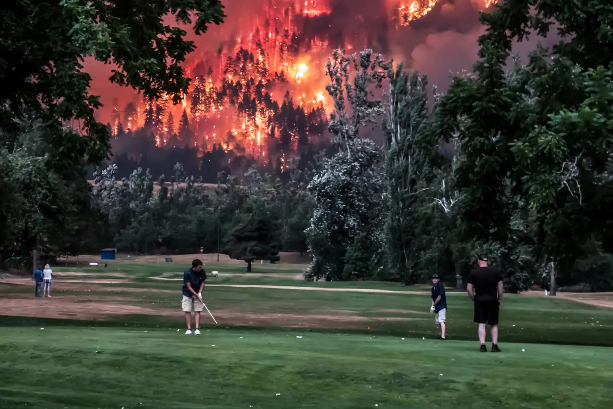 Setembro - Jogadores de golfe indiferentes às chamas que consomem uma vasta área florestal nos arredores de Washington, Estados Unidos.