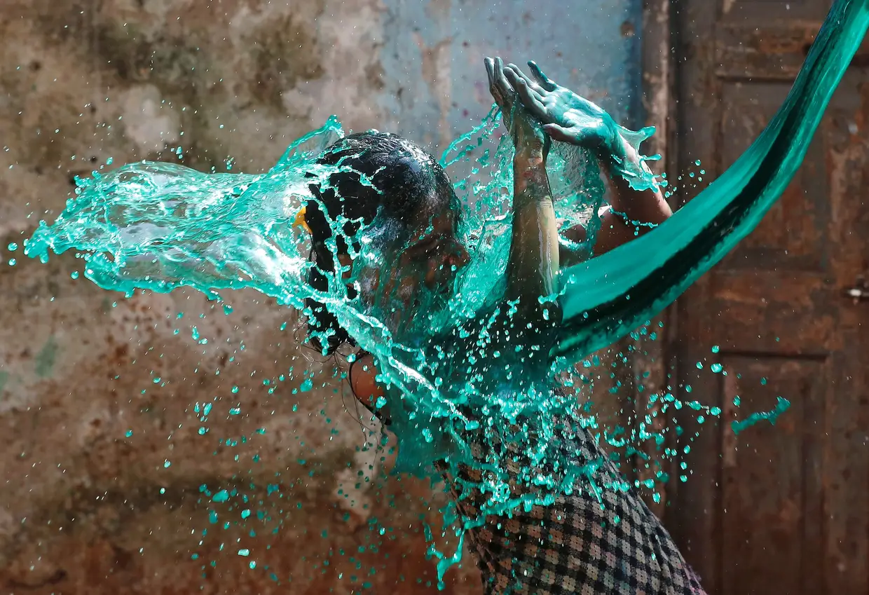 Jovem reage quando lhe atiram água colorida, costume tradicional nas celebrações do Holi Festival das Cores, em Bombaim, Índia.