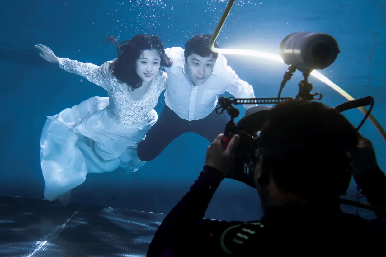 Cao Ri e Xu Jiaqian, recém casados, tiram uma fotografia num estúdio subaquático em Pequim, China.