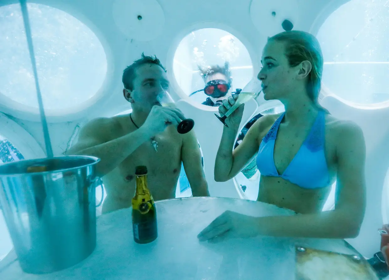 Florence Lutje Spelberg e Nicolas Mouchart bebem espumante numa sala esférica, situada a 5 metros de profundidade num centro aquático em Bruxelas, numa das piscinas com maior profundidade do mundo, especialmente concebida para treinar mergulhadores profissionais.