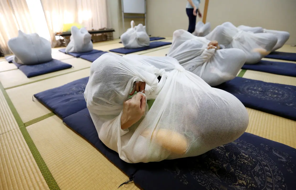 Sessão terapêutica em Asaka, no Japão, na qual é usado um novo método em que o paciente é envolvido num tecido largo e macio, com o objetivo de tratar ou aliviar problemas de postura e rigidez muscular.