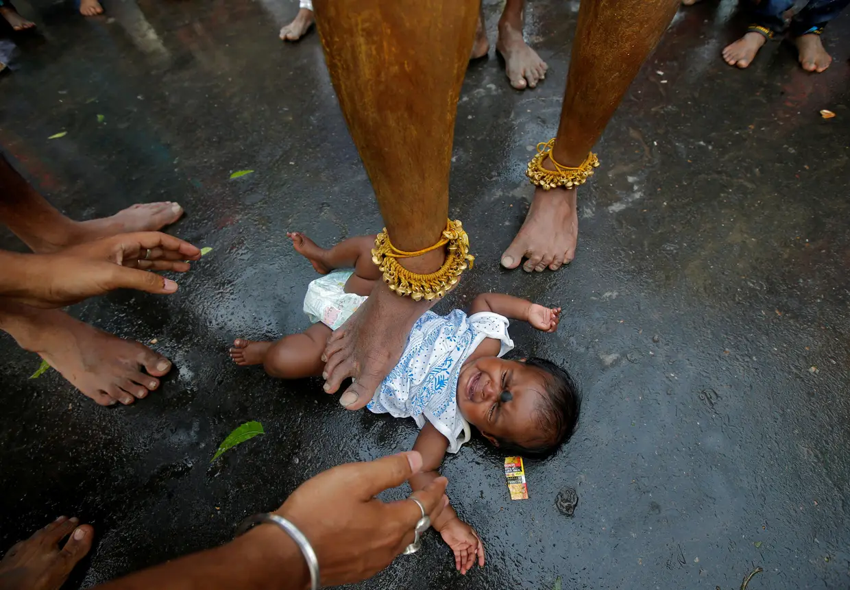 Um homem toca com o pé num bebé, num ritual que serve de bênção à criança, no âmbito de uma procissão religiosa do festival hindu de Bhel Bhel, na Índia