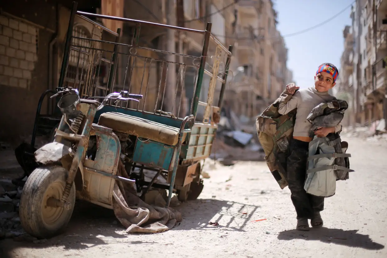 Um menino percorre uma das ruas danificadas de Douma, em Damasco, Síria.