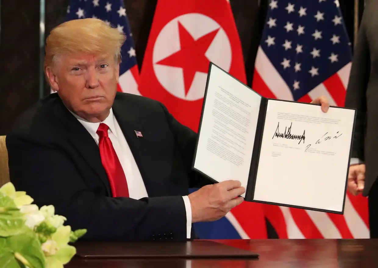 Donald Trump mostra aos fotojornalistas as páginas do documento já depois de assinado por ambas as partes.