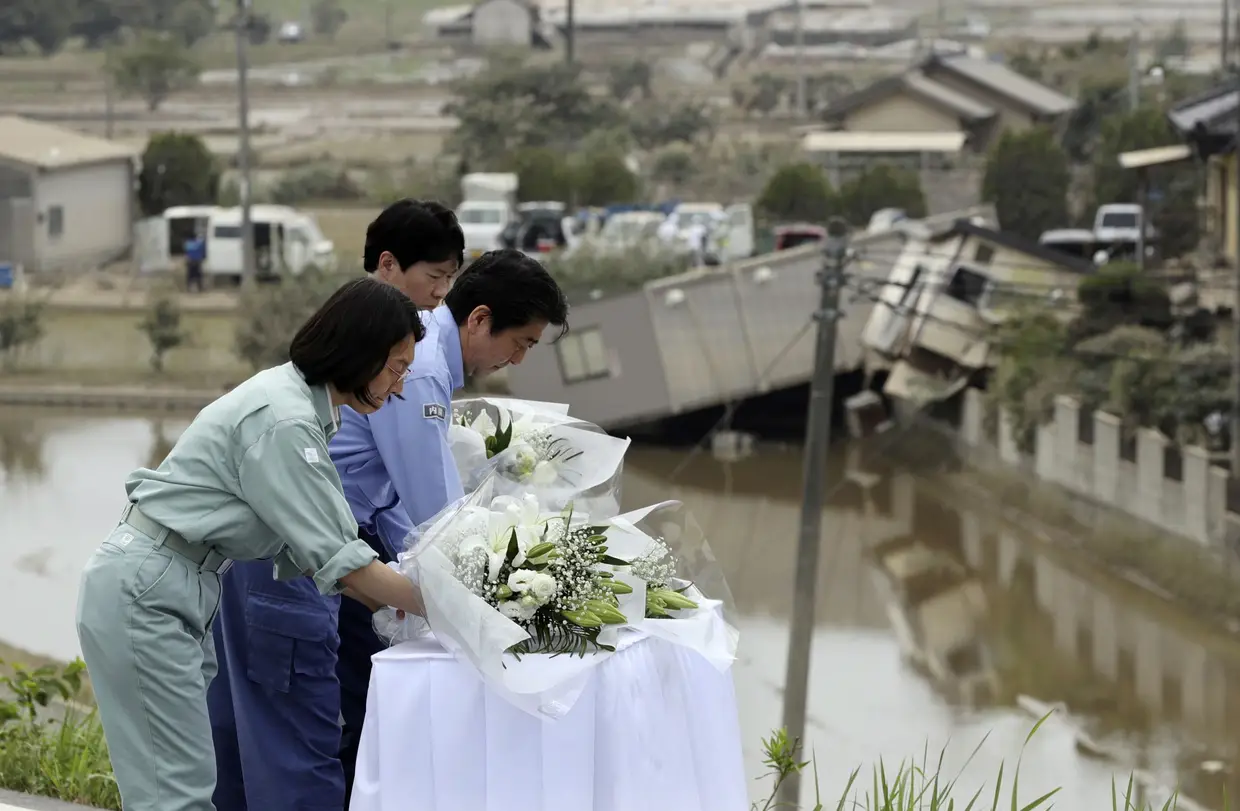 O primeiro-ministro japonês, Shinzo Abe, deposita flores em homenagem às vítimas das chuvas torrenciais no oeste do Japão. As chuvas, que levaram a cheias, já fizeram 179 mortes.