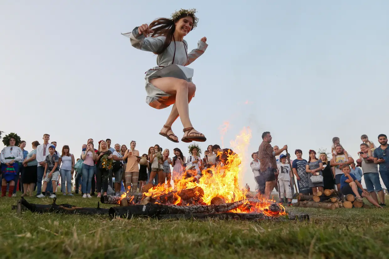 Uma mulher salta por cima de uma fogueira durante a celebração do feriado "Ivana Kupala" em Kiev, Ucrânia.