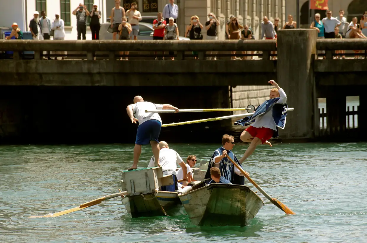 Um participante usa uma lança para empurrar o adversário do outro barco durante o evento tradicional Schifferstechen, semelhante a uma batalha medieval, no rio Limmat em Zurique, Suíça
