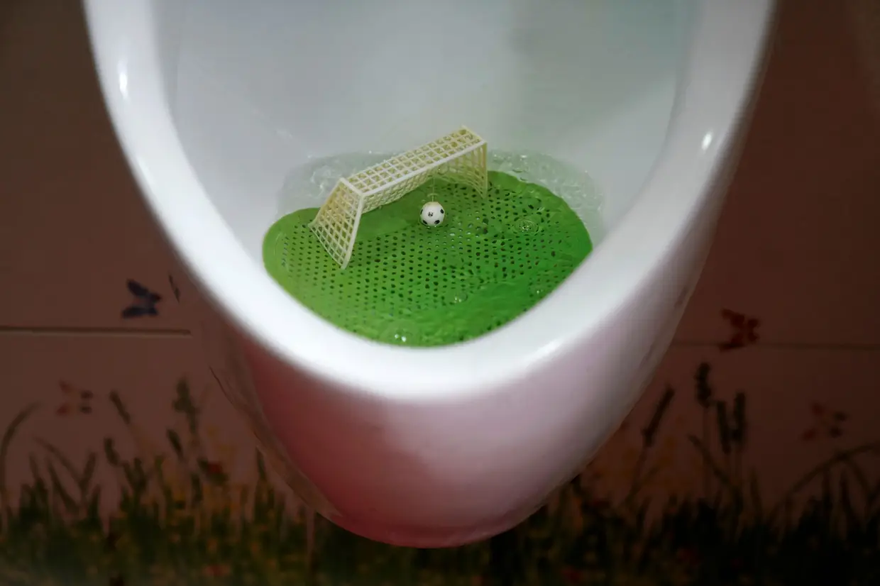 Um filtro de urinol desenhado como se fosse um campo de futebol com uma baliza e uma bola numa casa de banho, em Xangai, na China