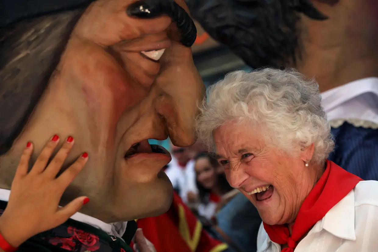 Um "Kiliki" faz uma mulher rir durante o festival de San Fermin "Comparsa de gigantes y cabezudos" (Desfile dos Gigantones e Cabeçudos) em Pamplona, Espanha