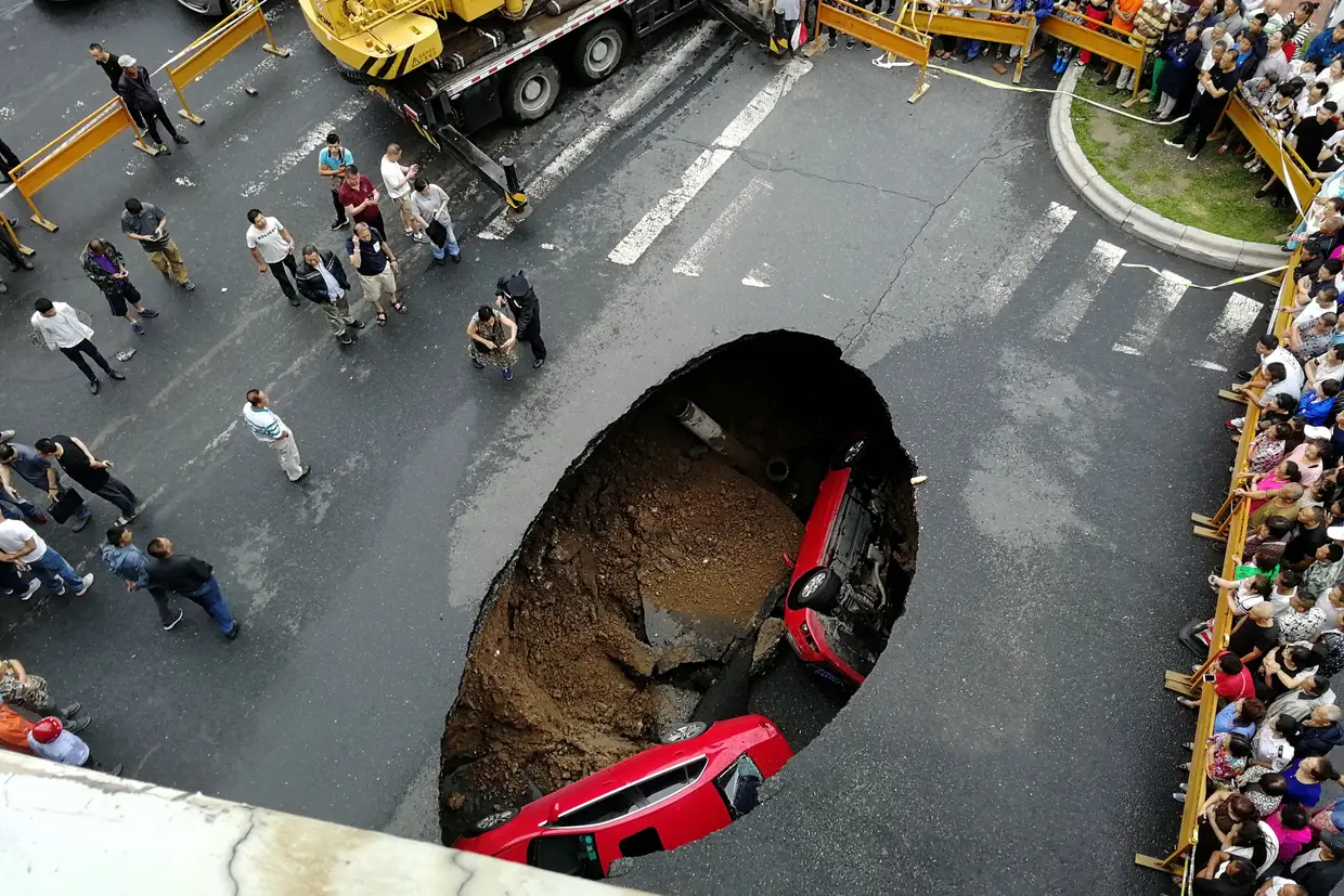 Duas viaturas caídas num buraco em plena estrada, na cidade chinesa de Harbin