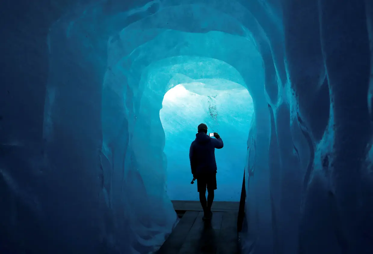 Um turista fotografa o interior de uma gruta de gelo no glaciar do Ródano, na Suíça.