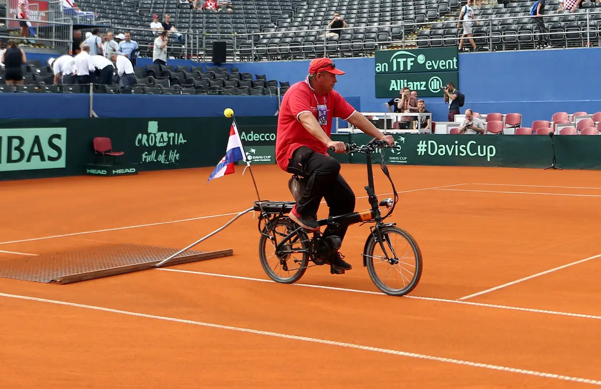 Um trabalhador faz a manutenção do piso antes de um jogo de ténis na Davis Cup.