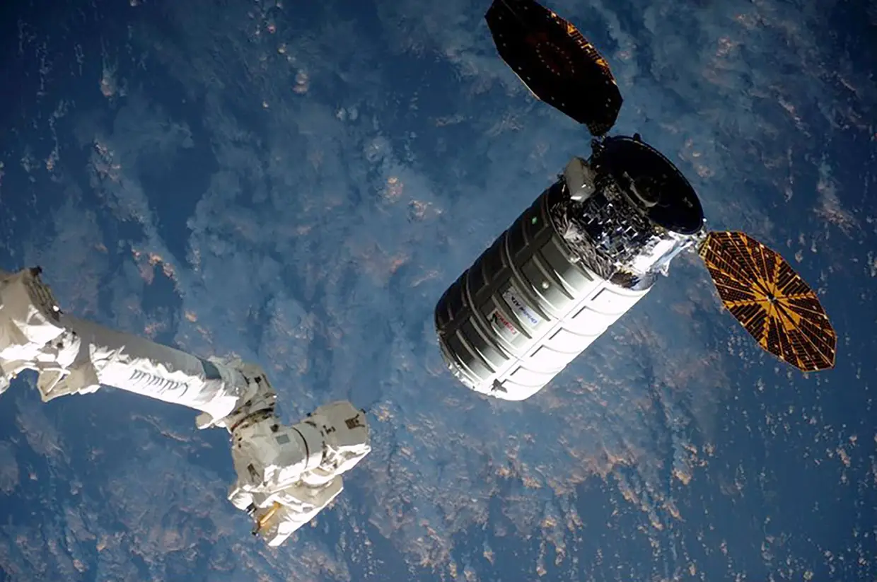 A nave não tripulada Cygnus prestes a ser apanhada pelo braço robótico da Estação. Leva mantimentos para reabastecer a Estação Espacial Internacional.