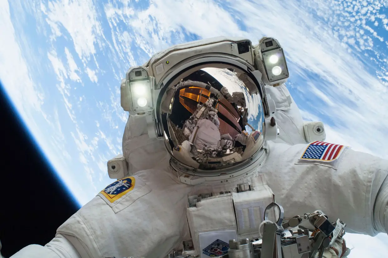 Astronauta Mike Hopkin num "passeio espacial" a 24 de dezembro de 2013. Refletido no seu capacete, o astronauta Rick Mastracchi, que ajudou nas reparações no exterior da ISS.