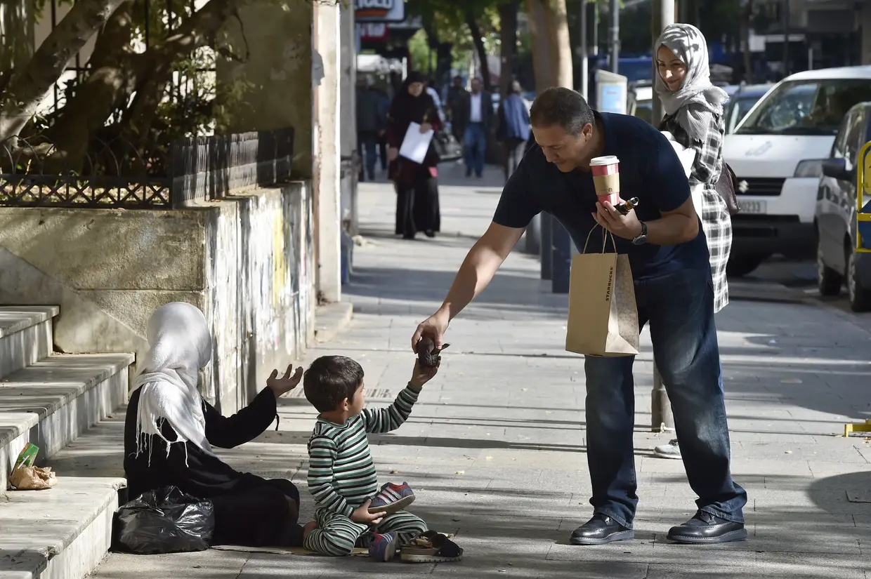 Um refugiado sírio pede na rua em Beirute, Líbano.