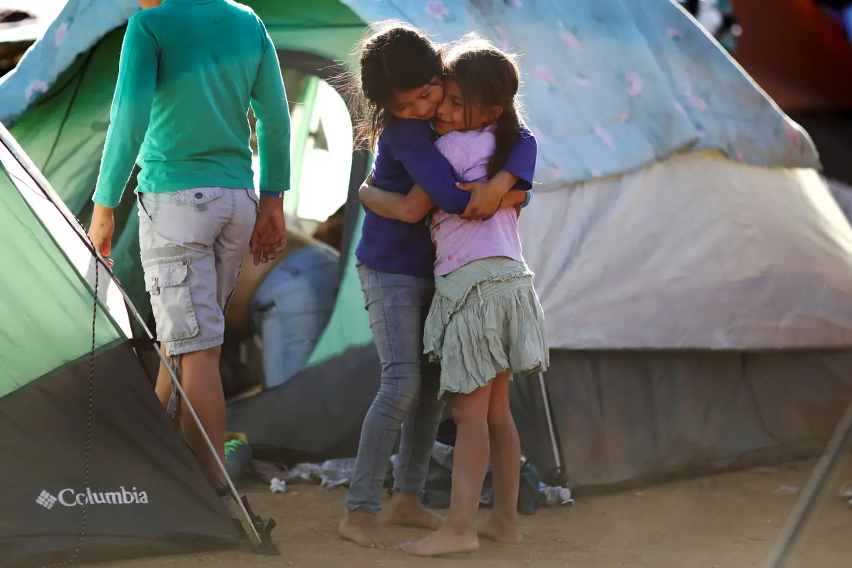 Duas crianças da caravana de migrantes da América Central abraçam-se num campo em Tijuana.
