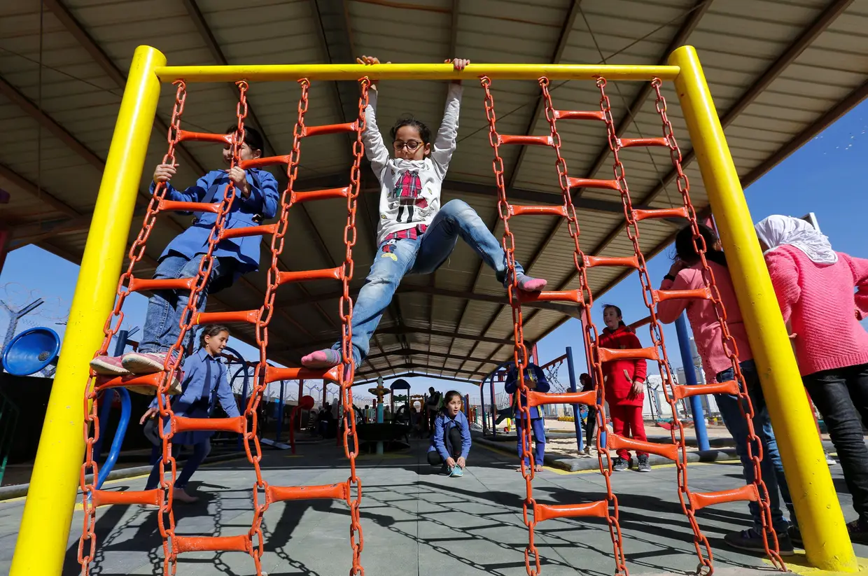Refugiados sírios brincam num parque infantil no campo de refugiados de Zaatari, na Jordânia.