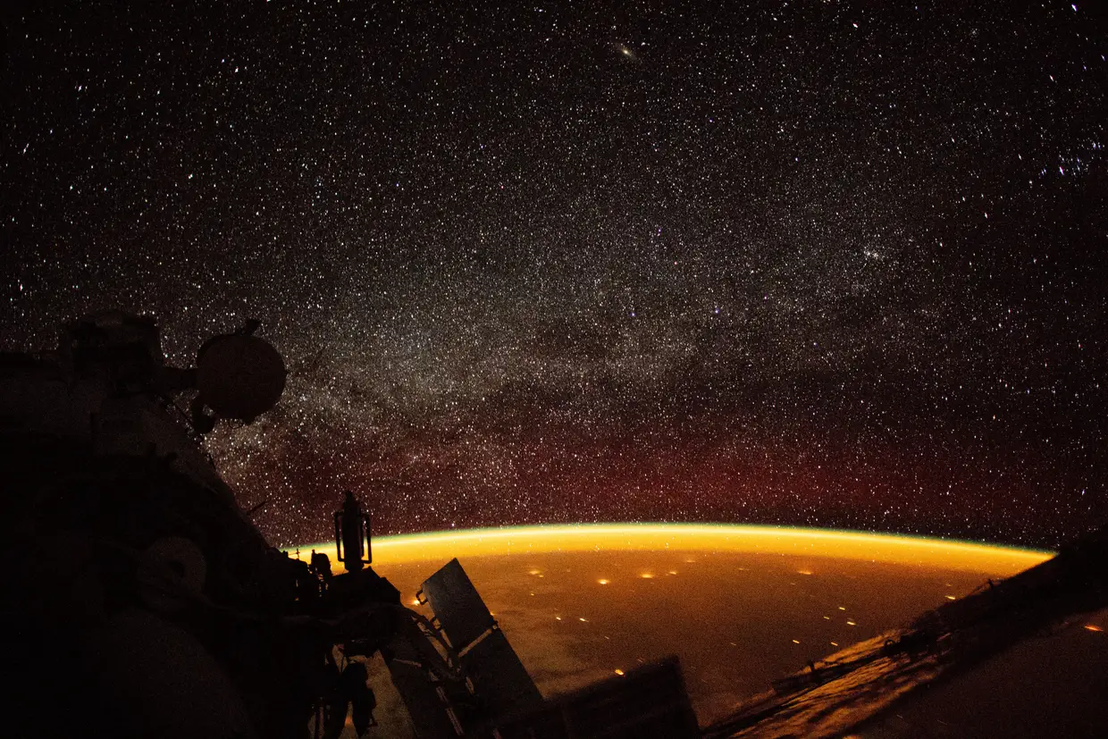 Uma linha laranja, conhecida como “airglow”, em português luminescência atmosférica, envolve a Terra. Este fenómeno acontece quando a radiação ultravioleta atinge moléculas na atmosfera.