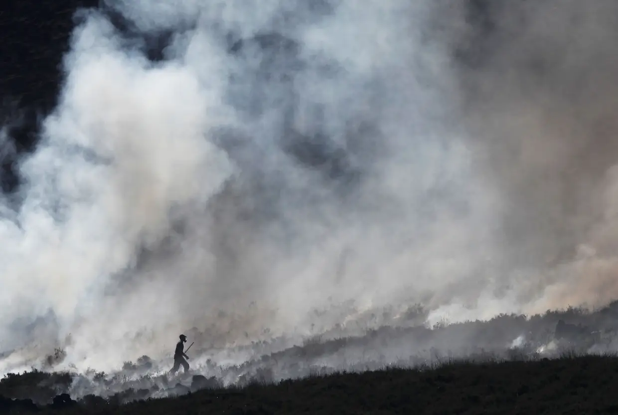 Um bombeiro no rescaldo de um incêndio na Grã-Bretanha, Reino Unido.