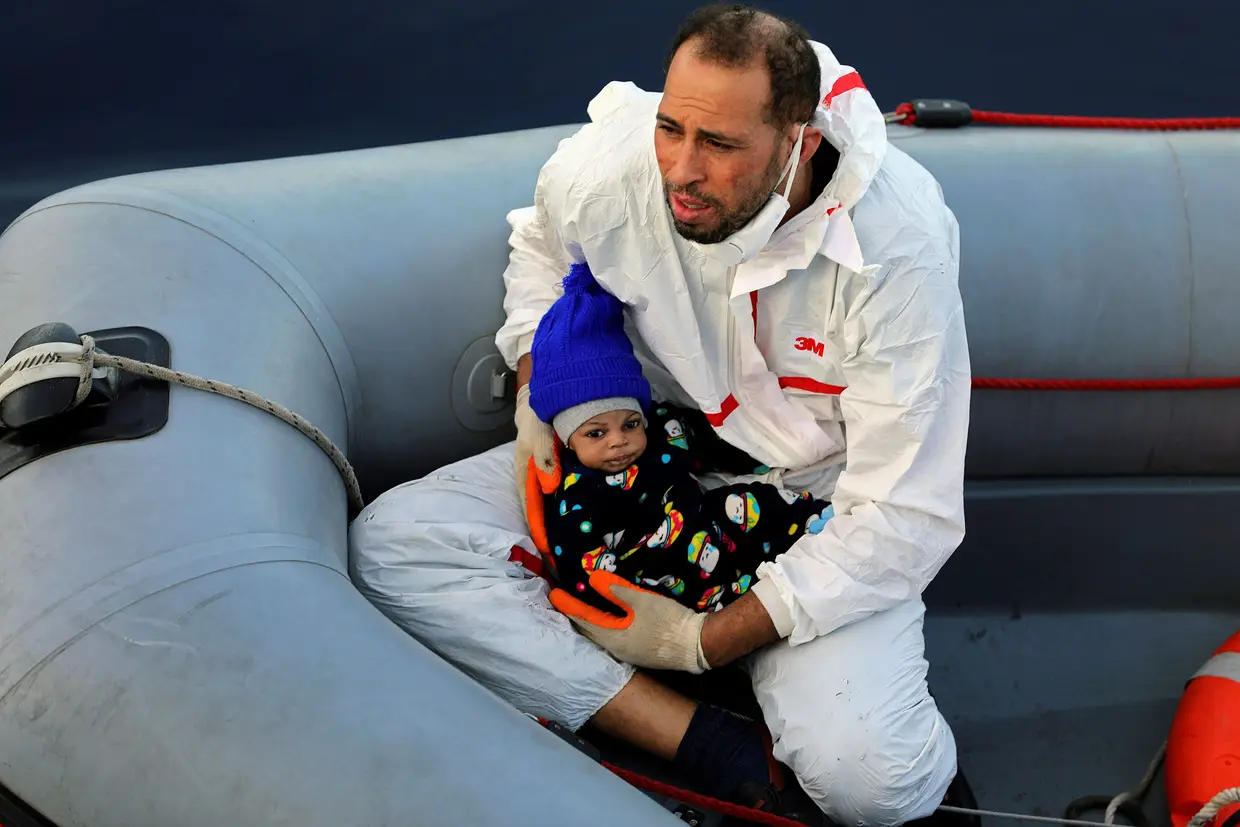 Um membro de uma equipa de salvamento leva um migrante bebé resgatado no Mar Mediterrâneo, ao largo da costa da Líbia.