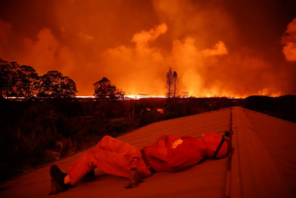 Um bombeiro descansa no telhado de uma casa em Pahona, no Havai, de onde se pode ver a lava do vulcão Kilauea.