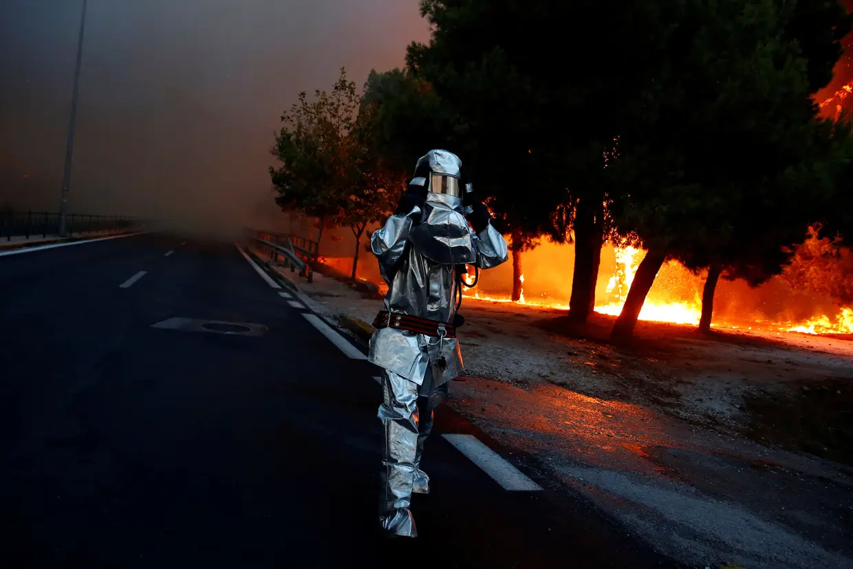 Um bombeiro usa um fato à prova de fogo durante um incêndio em Rafina, perto de Atenas, Grécia.
