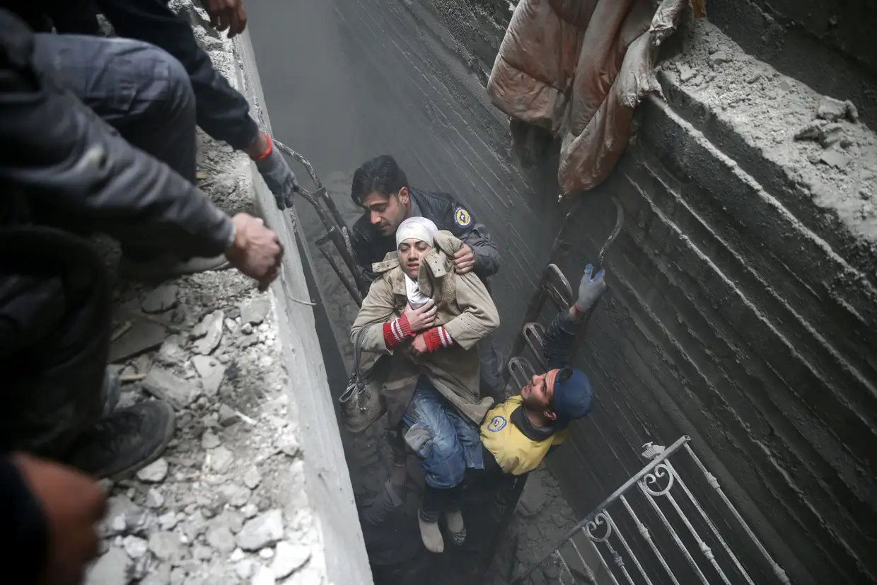 Elementos da Proteção Civil ajudam uma mulher inconsciente em Douma, Damasco, Síria.