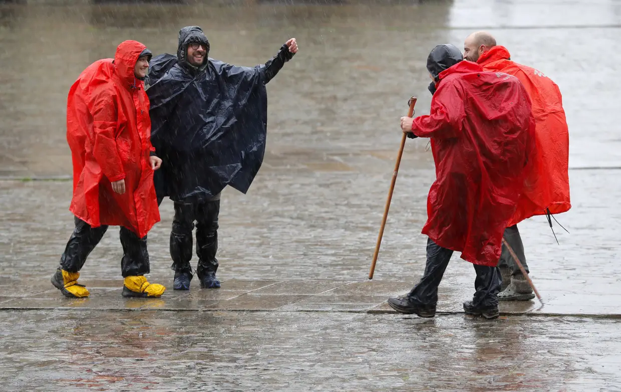 Peregrinos conversam à chuva ao chegarem à Praça do Obradoiro, em Santiago de Compostela.