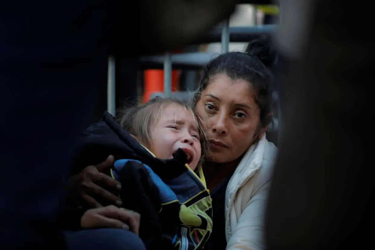 Maria Meza, uma migrante de 40 anos das Honduras, que faz parte da caravana da América Central que tenta chegar aos Estados Unidos, segura na sua filha enquanto espera no porto de entrada de Otay Mesa, em San Diego, na Califórnia.