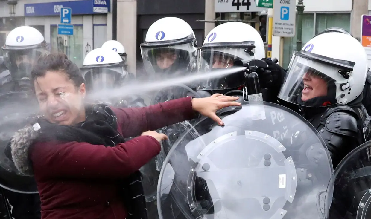 Uma mulher é atingida com gás pimenta durante o protesto dos coletes amarelos em Bruxelas, na Bélgica.