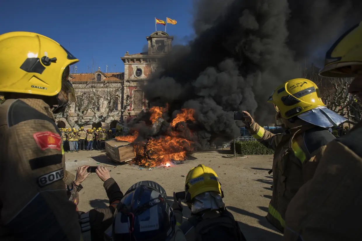 Bombeiros queimam material inflamável e uma réplica de um caixão durante um protesto em frente ao Parlamento da Catalunha, em Barcelona. Os bombeiros espanhóis exigem melhores condições de trabalho.