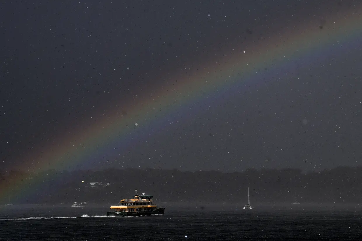 Um ferry é visto sob um arco-íris durante uma tempestade em Sydney, Austrália.