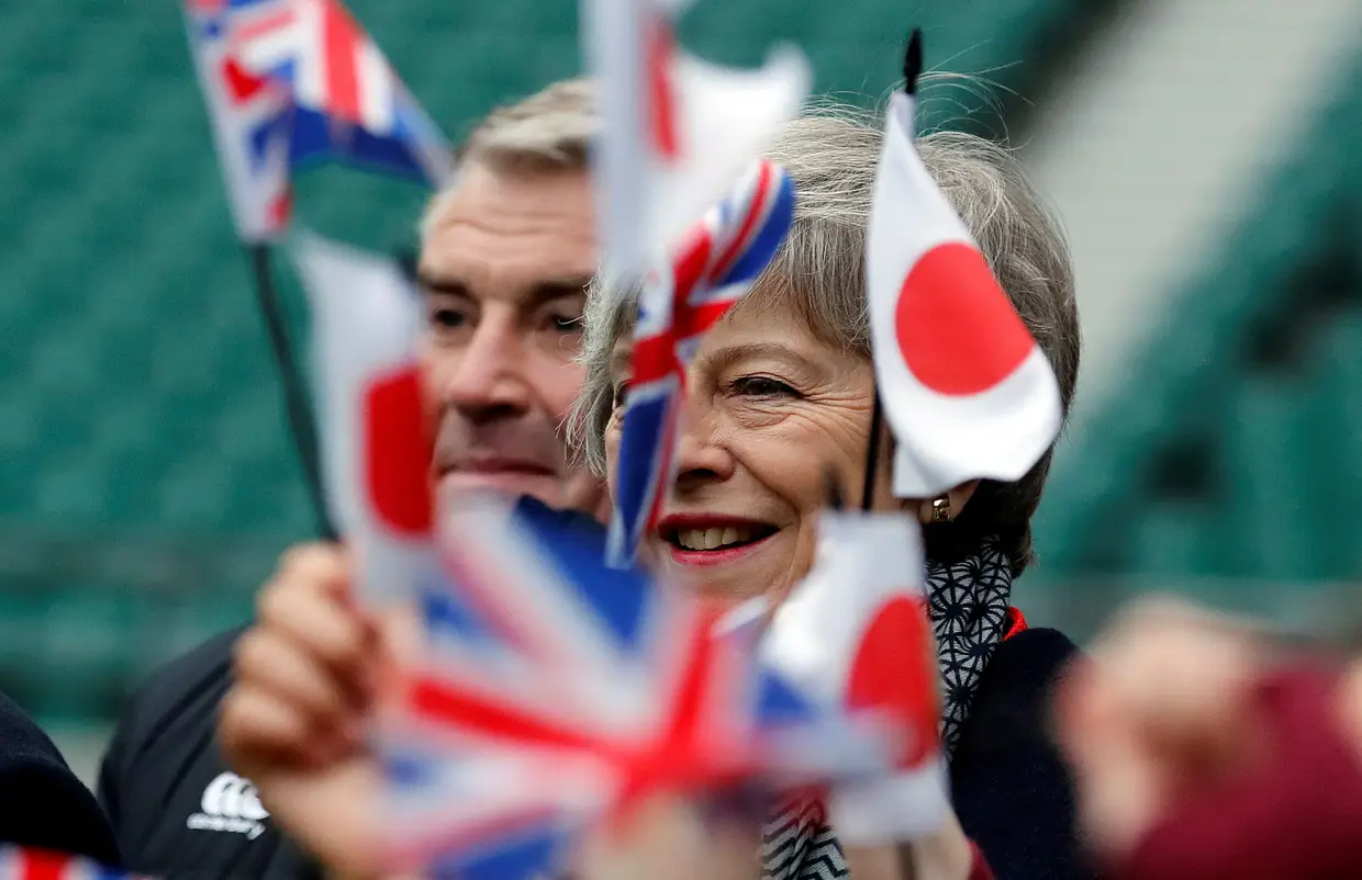 A primeira-ministra britânica Theresa May e o ex-jogador de rugby Jason Leonard assistem a um jogo de rugby infantil em Londres.