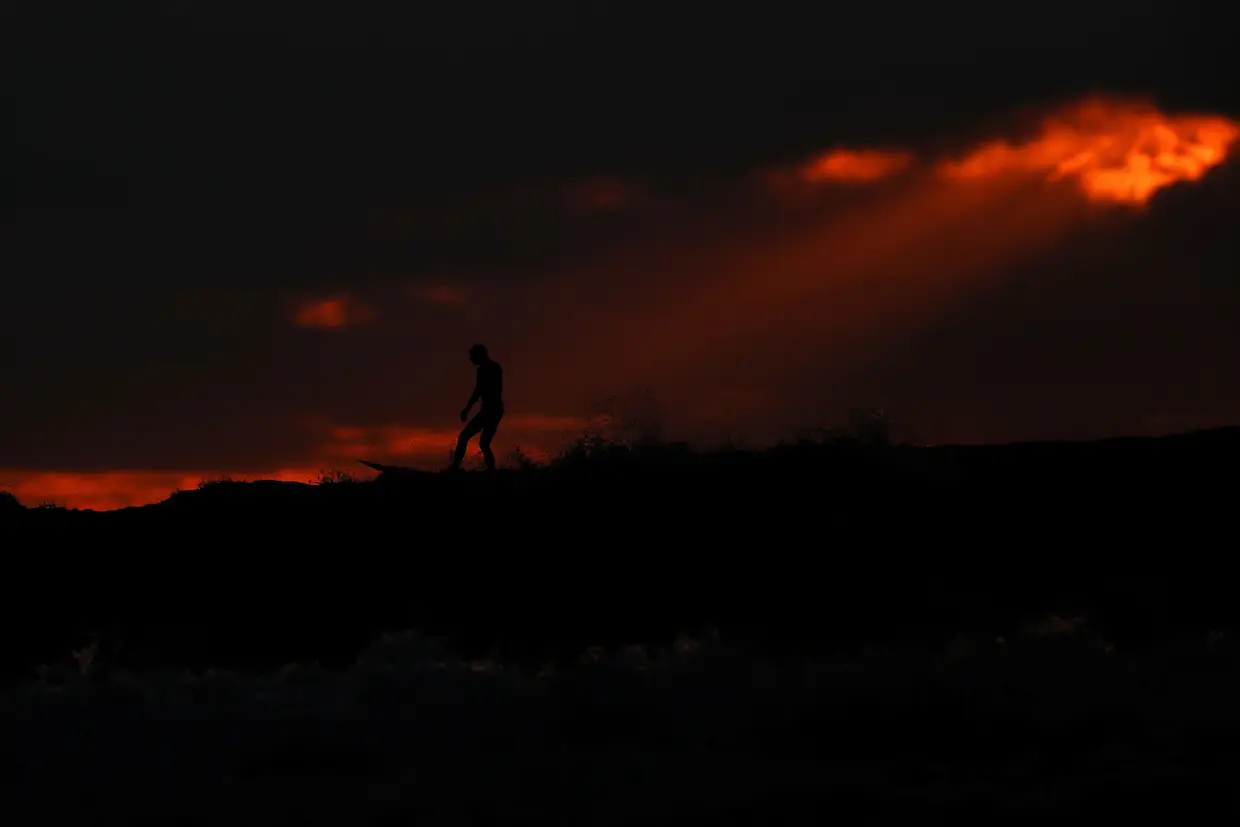 Um surfista fotografado durante o pôr do sol em Cardiff, Califórnia.