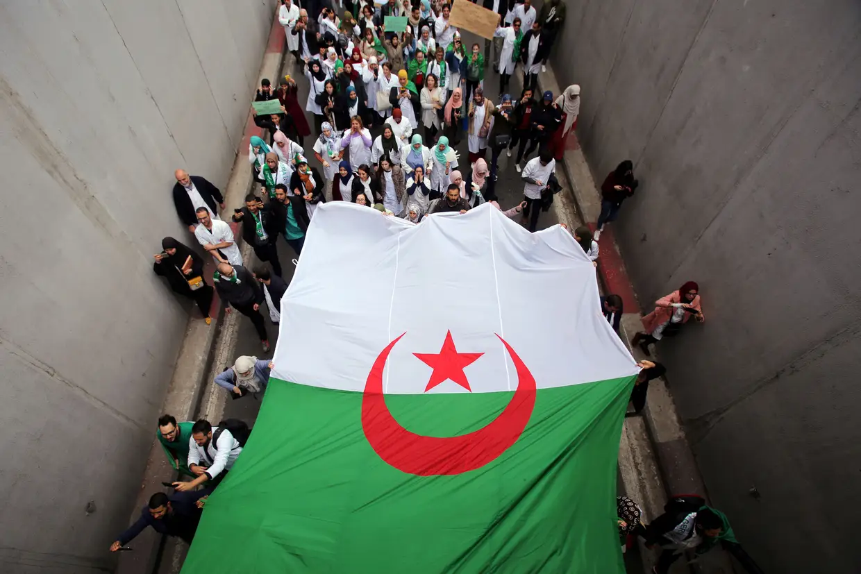 Trabalhadores da saúde marcham com a bandeira da Argélia durante um protesto pela demissão do presidente Abdelaziz Bouteflika.